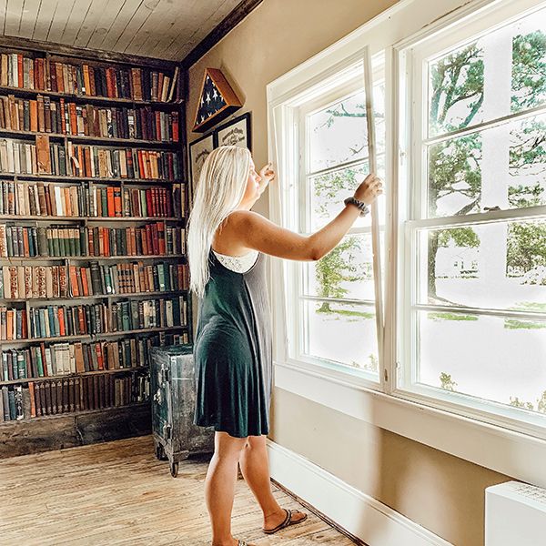 woman installing soundproof window inserts to reduce noise in apartment